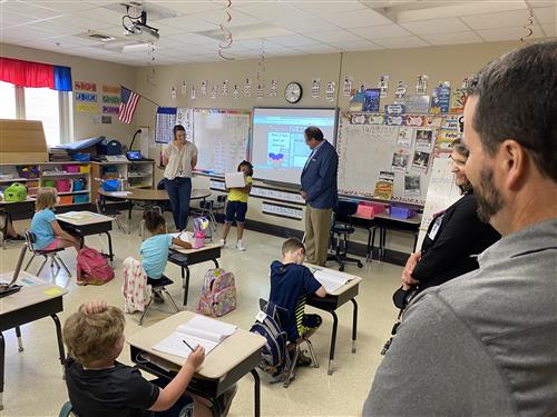 Board President Tim Holtcamp in back of classroom observing teacher and students 